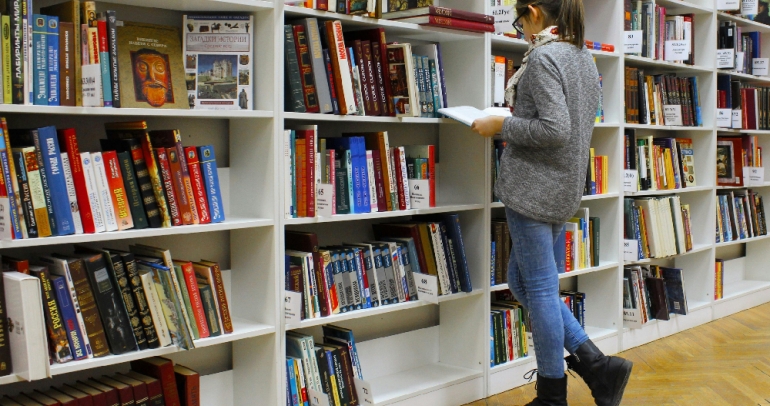 Une usagère lit un livre à côté d'étagères