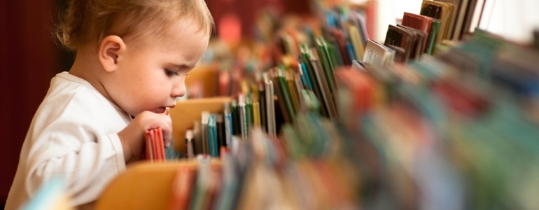 bébé qui regarde un libre dans un rayon de la médiathèque 